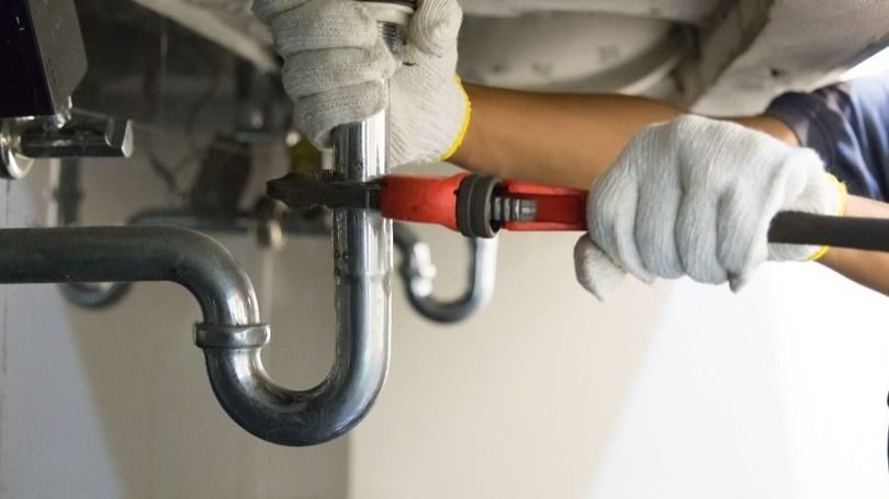plumber fixing a pipe underneath a sink