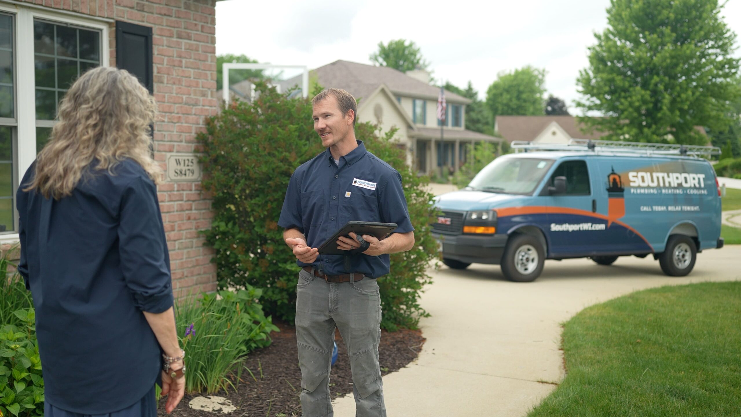 Service technician speaks with homeowner outside a brick house; a Southport van is parked on the driveway.