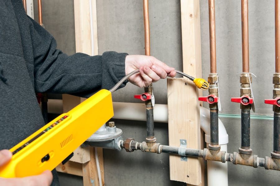 A technician checking the gas line in a home inspection.