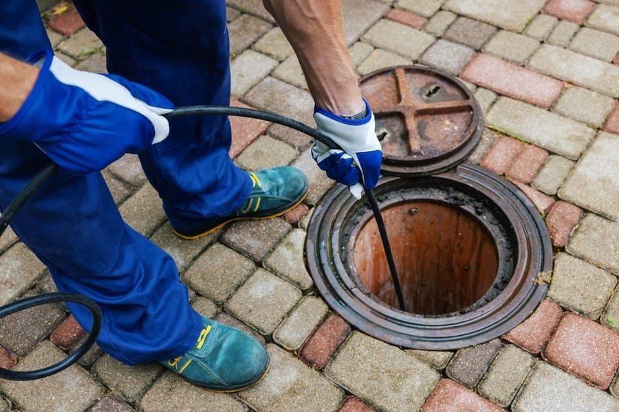 Southport plumber using expert tools to clear sewer line.
